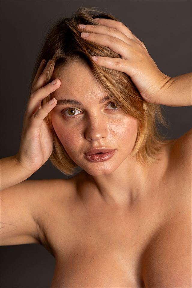 Frau mit beiden Händen im Haar, direkter Blick