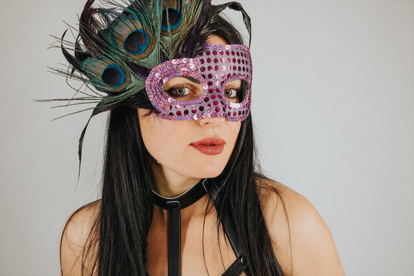 Frau mit pinker Maske und Pfauenfedern